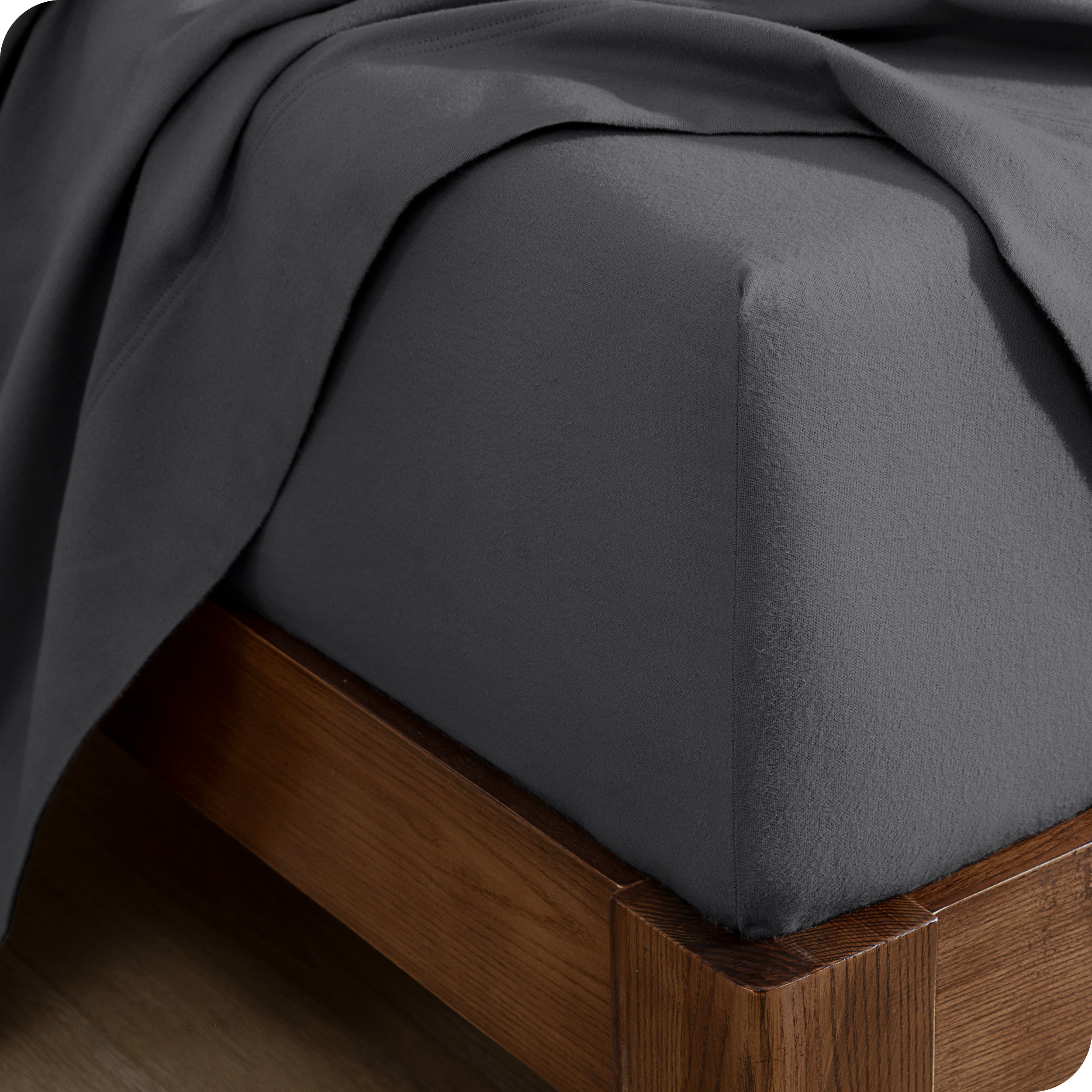 Close up of the corner of a mattress with a fitted sheet and flat sheet on it