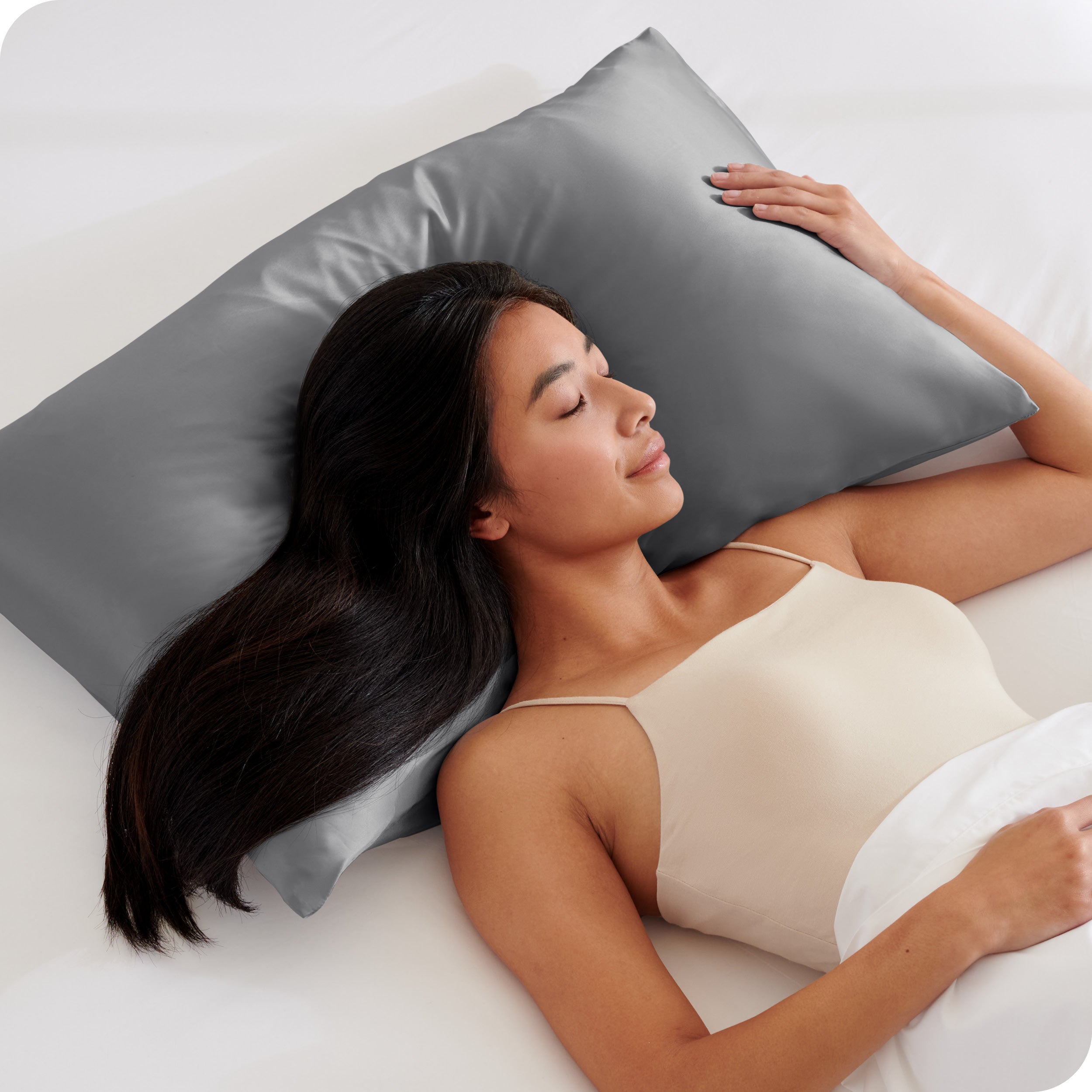 A woman sleeping with her head on a pillow with a silk pillowcase on it
