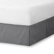 The corner of a bed skirt on a bed frame