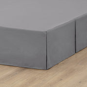 A box spring with a bed skirt on it