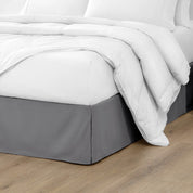 The corner of a bed with a bed skirt and comforter on it