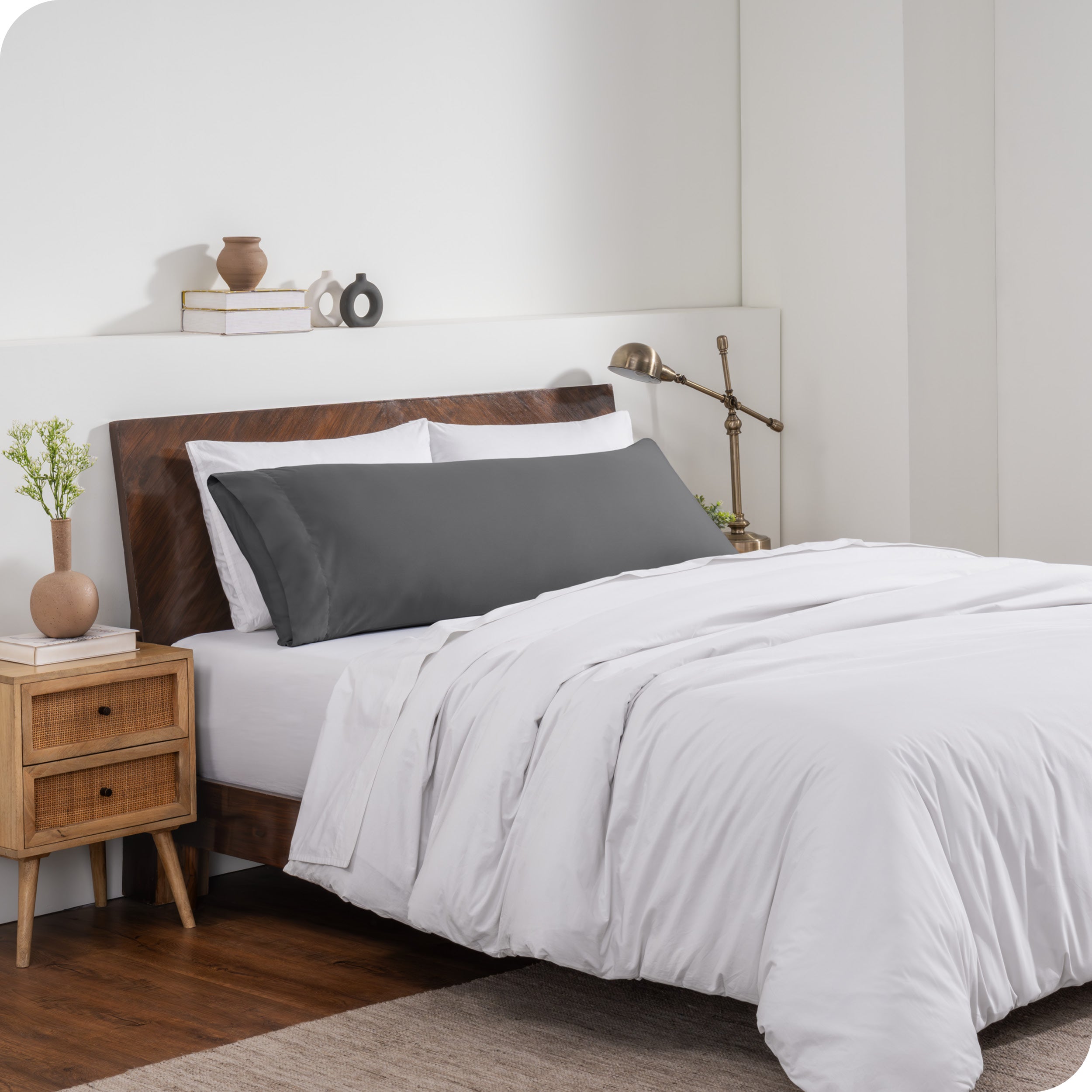 A body pillow cover on a pillow on a bed made with all white bedding