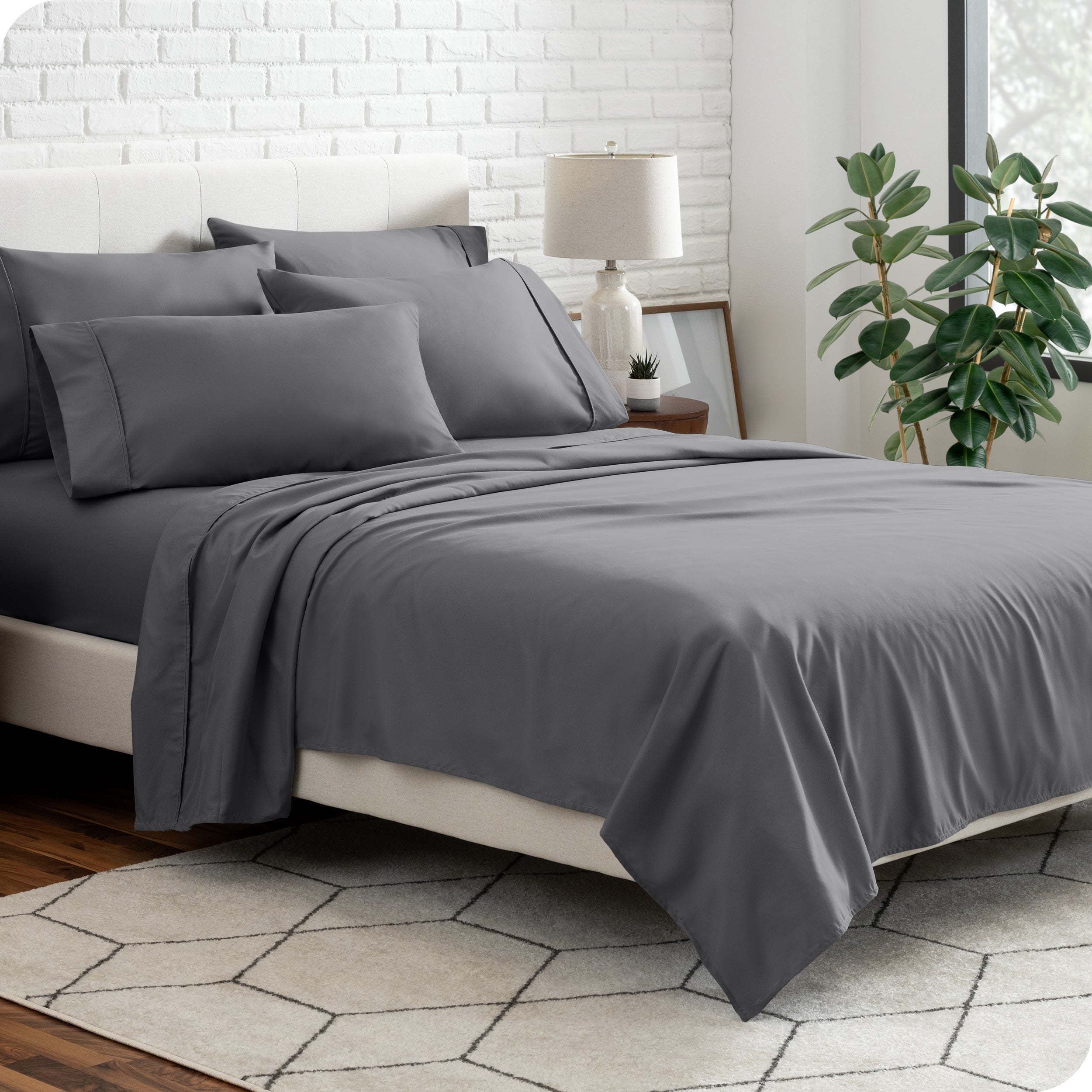 A bedroom setting with a bed made with the microfiber bed sheets and four pillows.