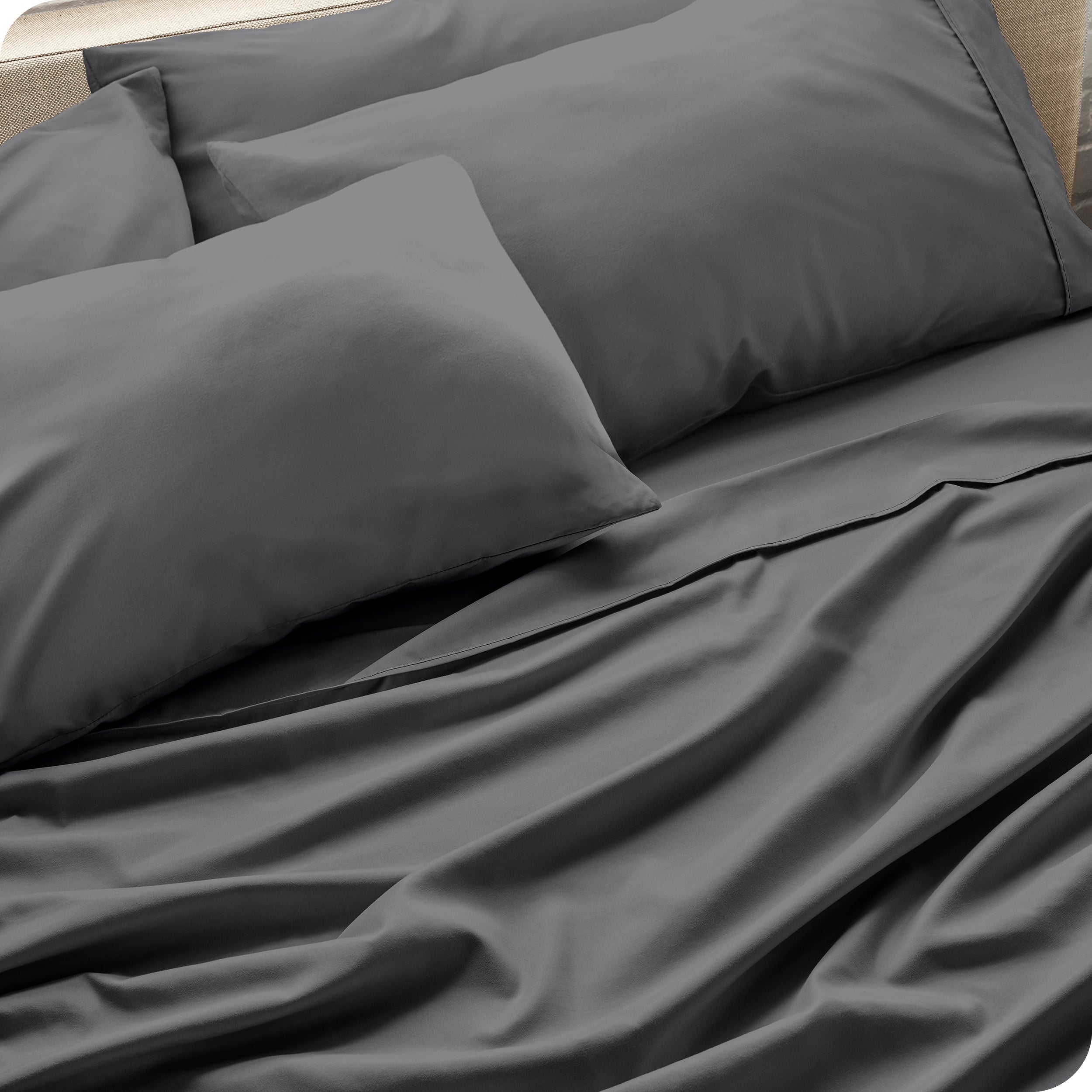 Close up of the microfiber bed sheets on a bed with four pillows.