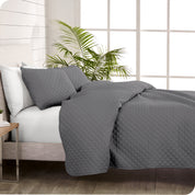 A coverlet set on a bed next to a window