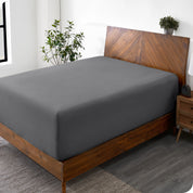 A wide corner view of a modern bed made with a microfiber fitted sheet on the mattress. 