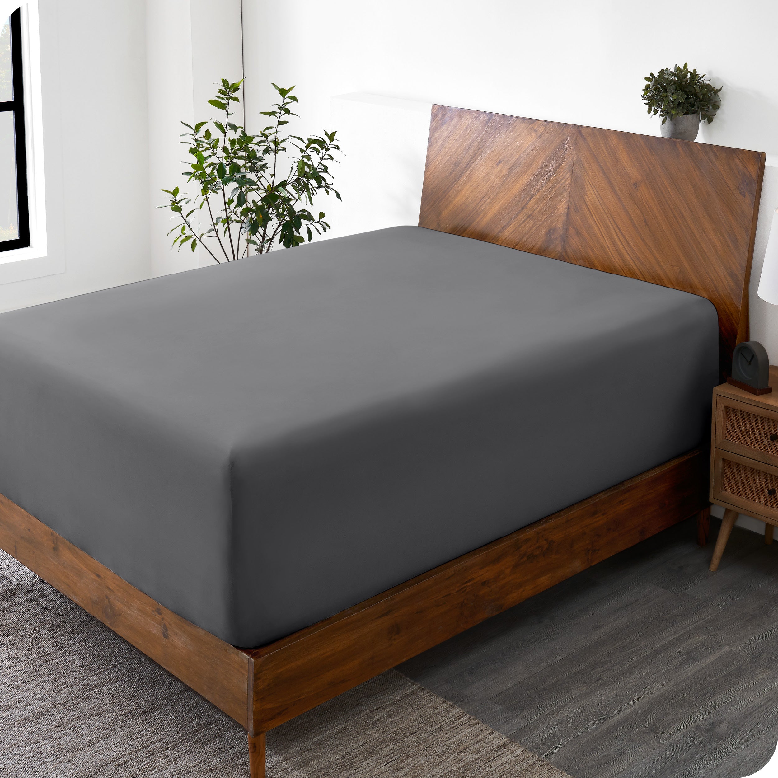A wide corner view of a modern bed made with a microfiber fitted sheet on the mattress. 