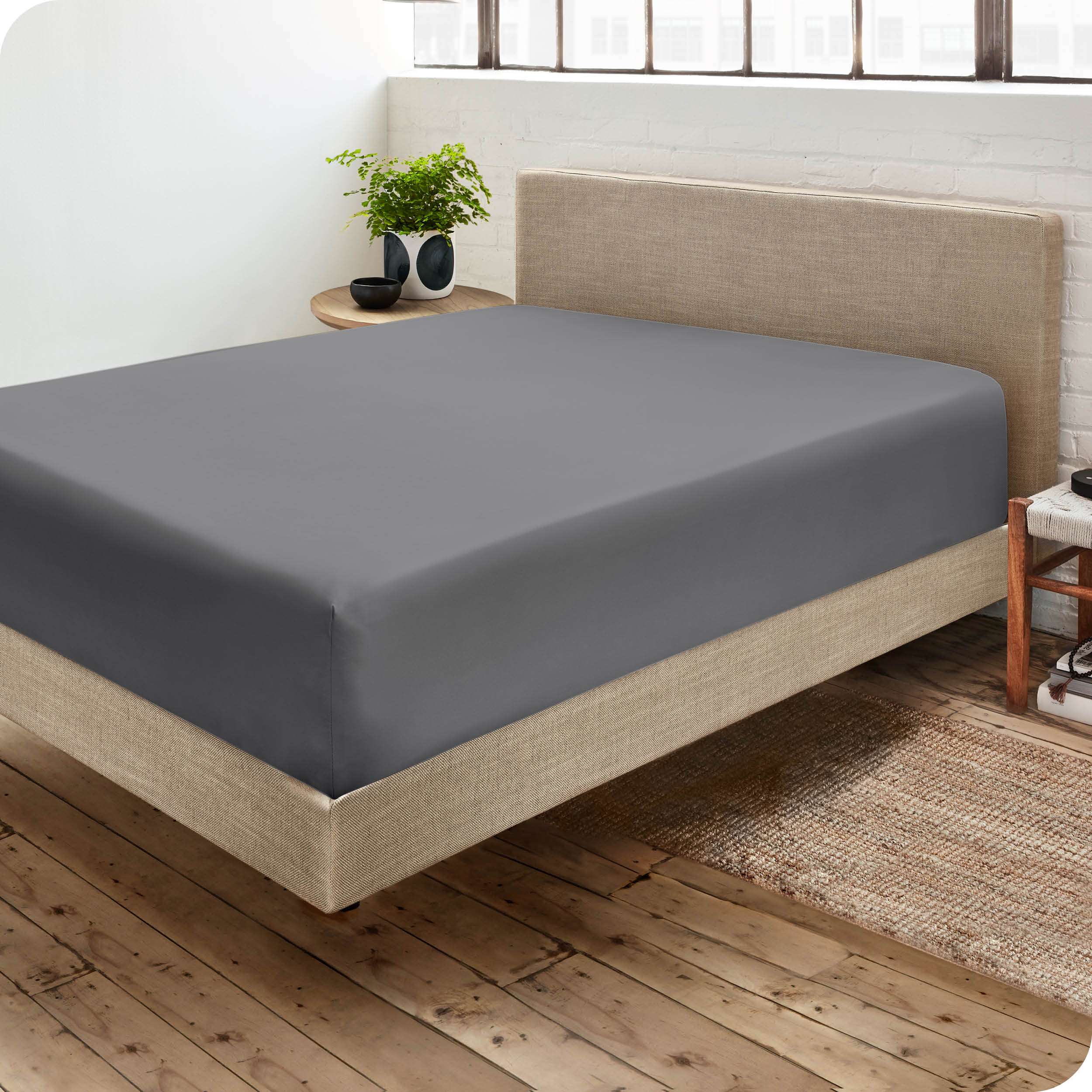 Corner view of a modern bed with a microfiber fitted sheet on the mattress. 