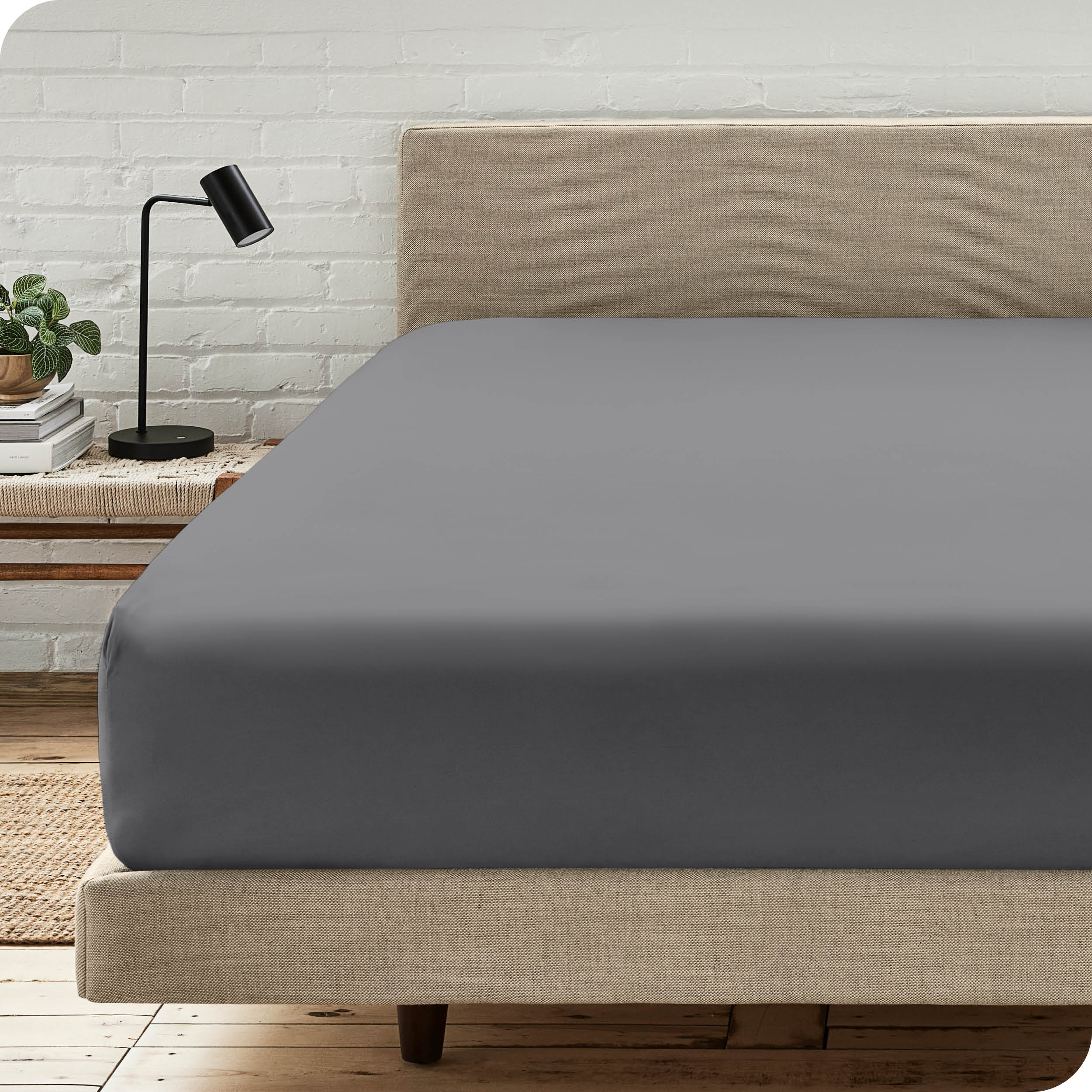 A bed with a microfiber fitted sheet on the mattress. 