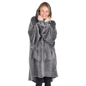 A woman is snuggled up in a hooded microplush wearable blanket
