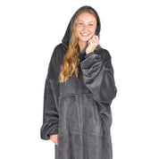 An adult is standing while wearing a microplush wearable blanket