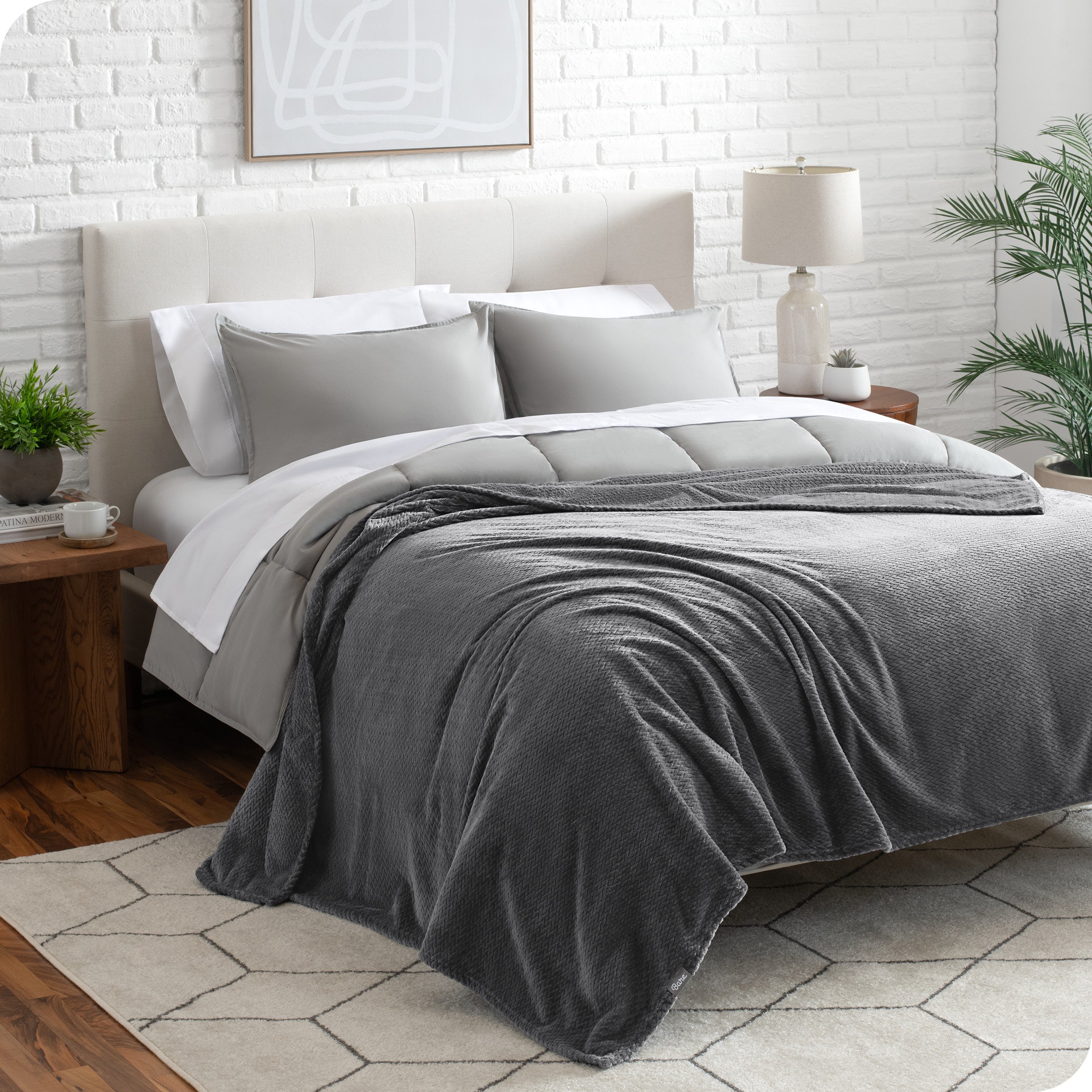 A textured microplush blanket is draped over a bed made with grey duvet set