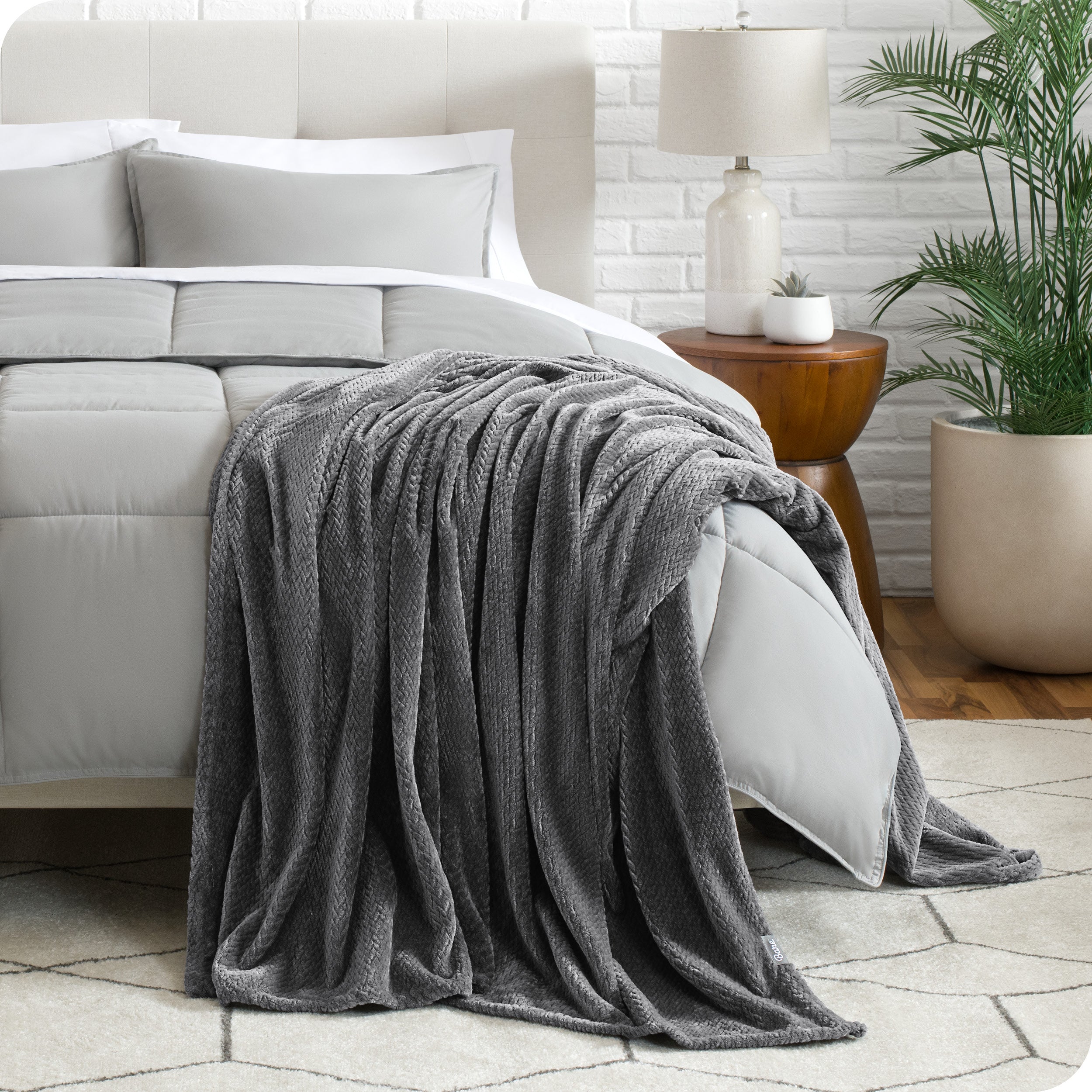 A textured microplush blanket is hanging over the corner of a bed