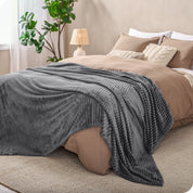 A microplush blanket spread out over the end of a bed
