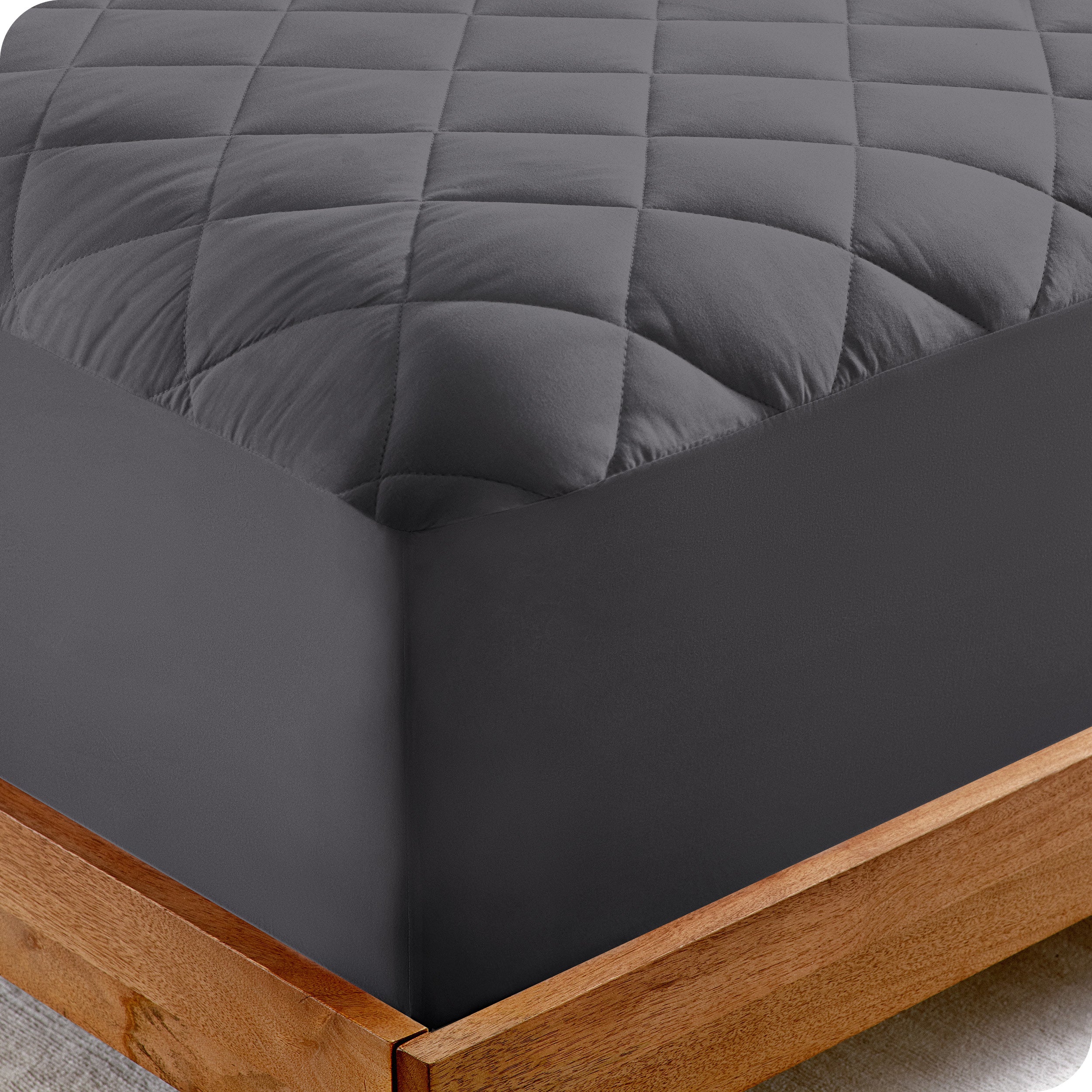 The corner of a bed showing the texture of the quilted mattress pad.
