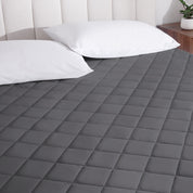 A mattress pad on a bed with two pillows from above.