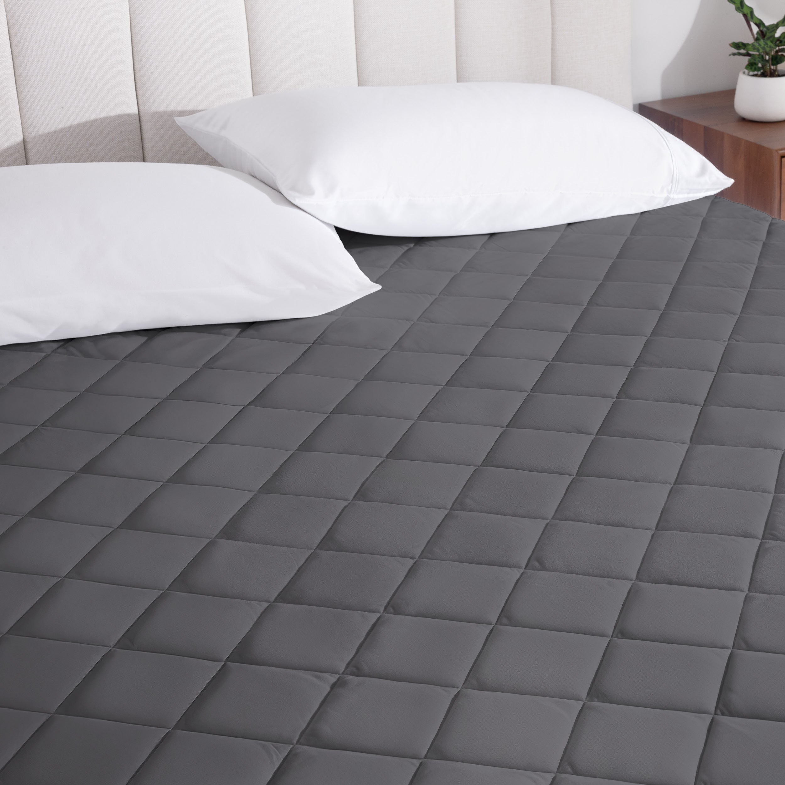 A mattress pad on a bed with two pillows from above.