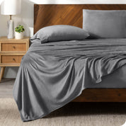 A grey sheet set on a bed with a wooden bed frame