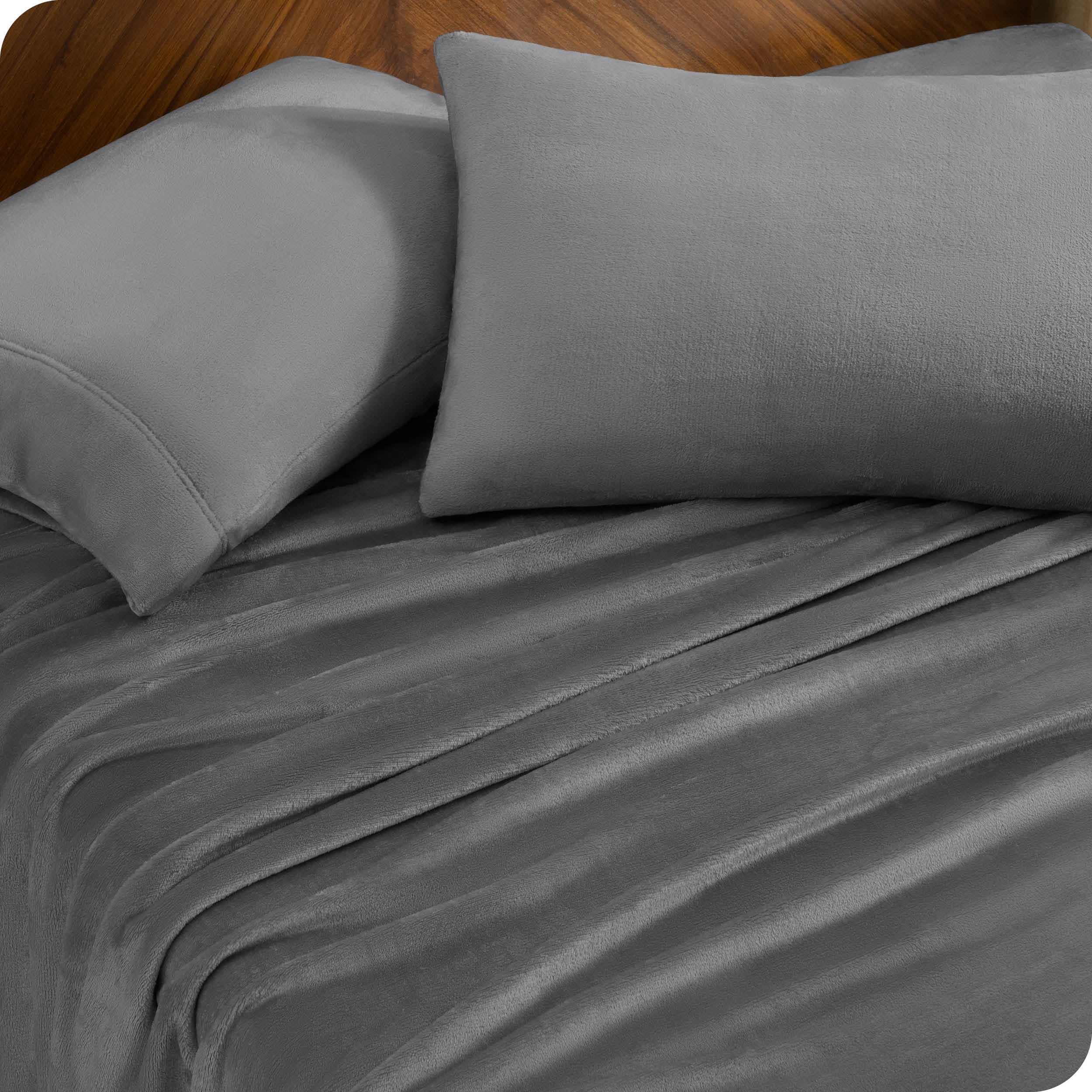 Two pillows with pillowcases on them set on a bed with matching sheets