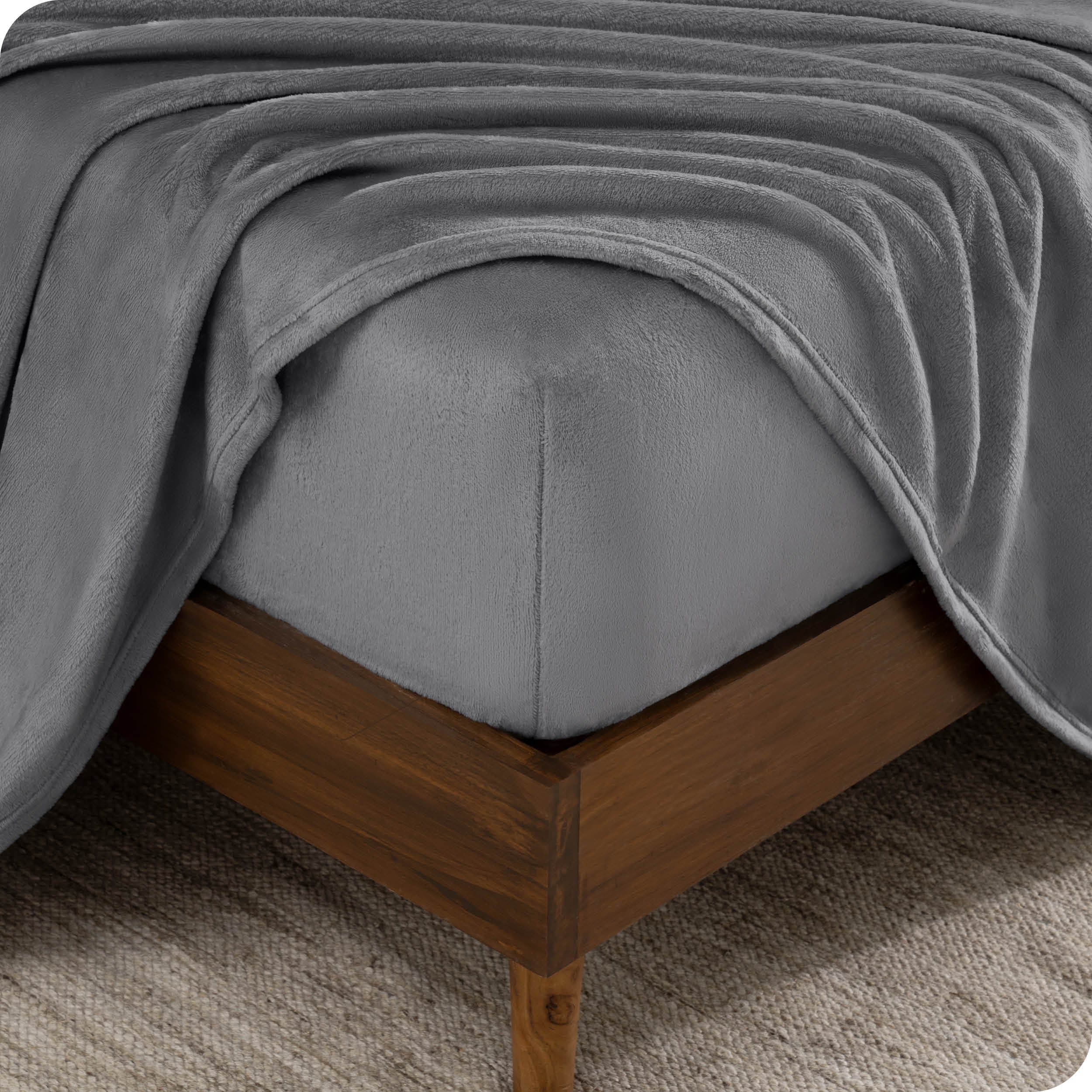 A corner of a mattress with a fitted sheet and a flat sheet on it.