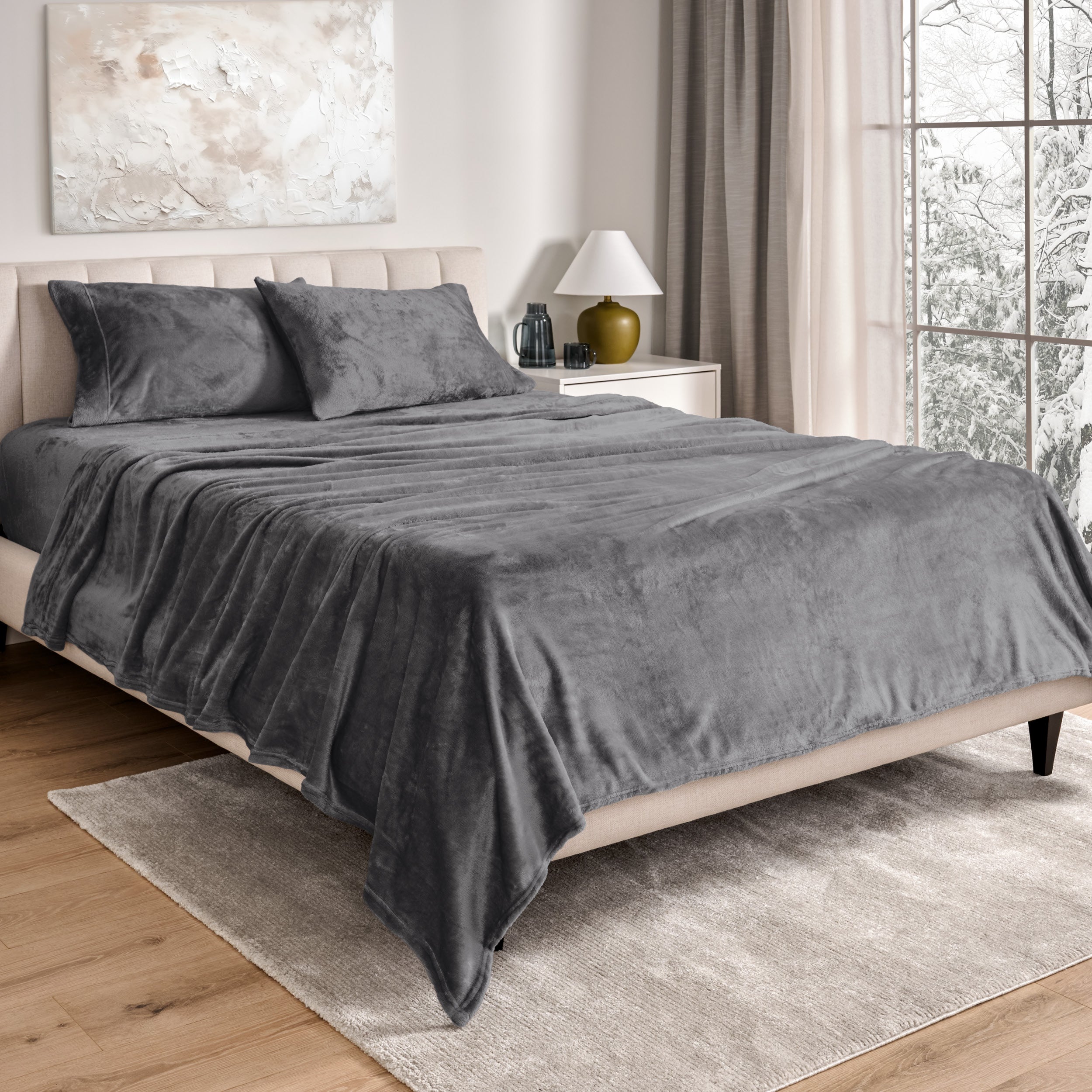 Sheets and matching pillowcases on a bed in a bedroom with a lamp and window in the background.