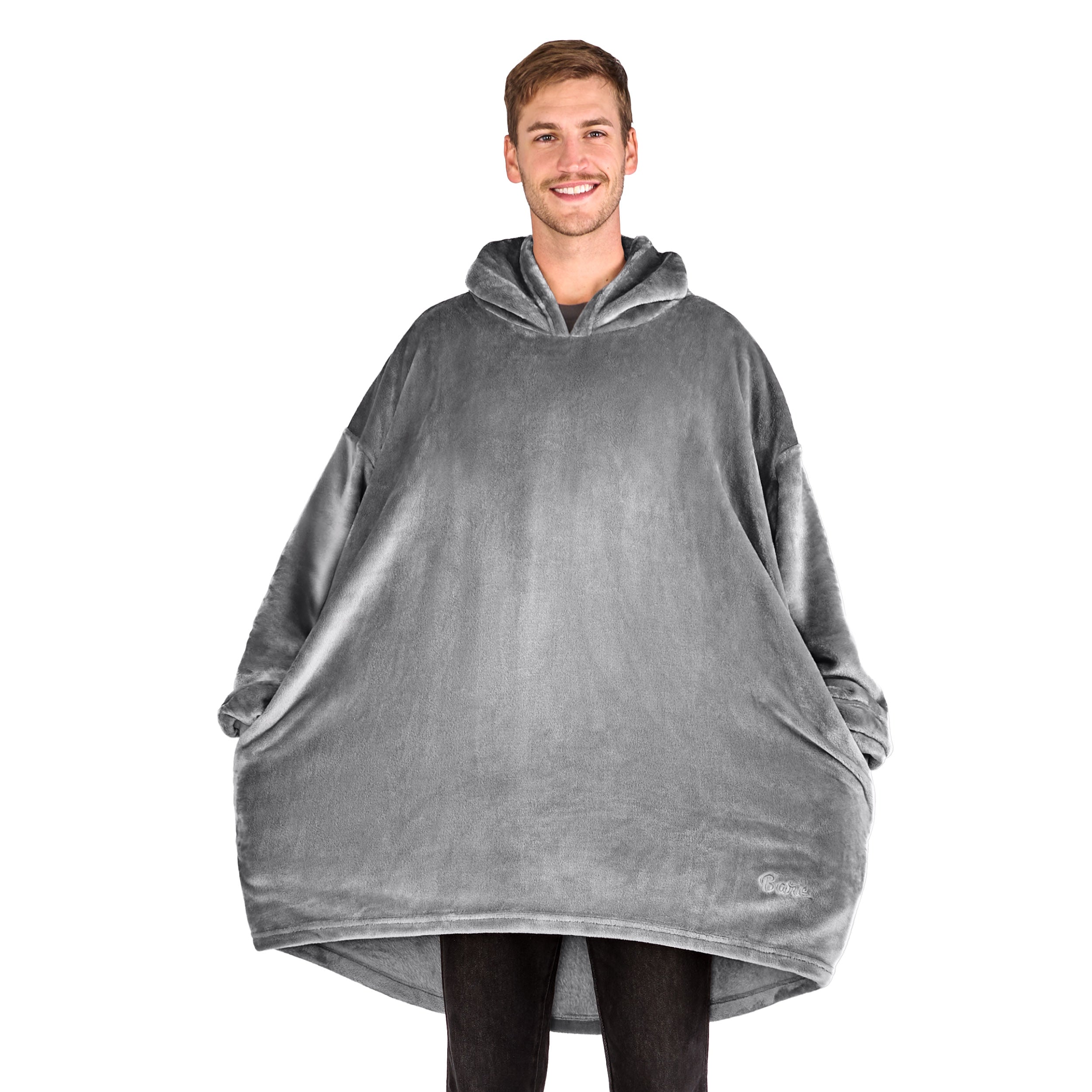 A man has a microplush wearable blanket on and his hands are in the side pockets