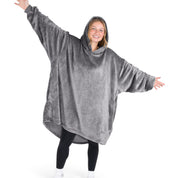 A woman is standing with her arms stretched out and has a hooded wearable blanket on