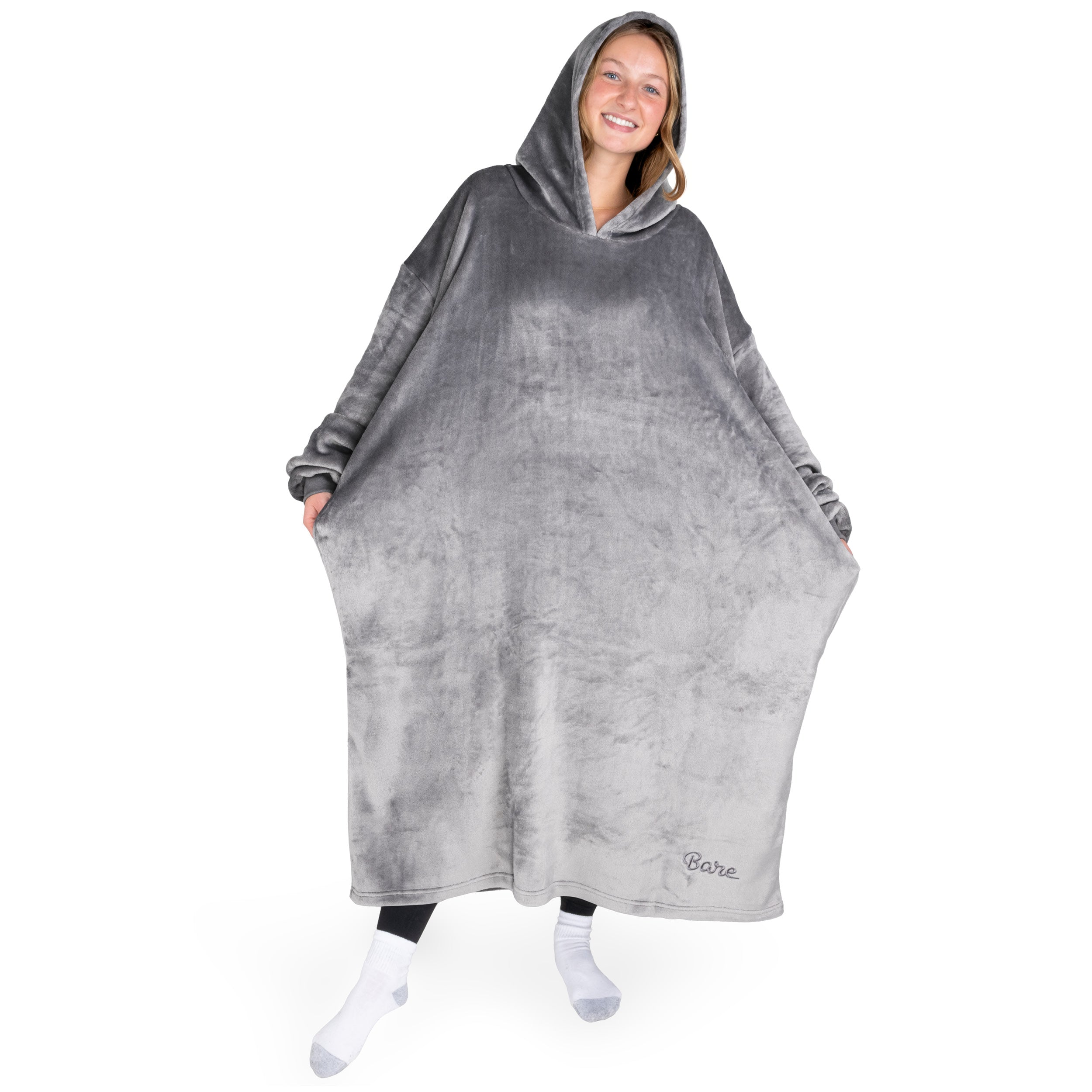 An adult is standing while wearing a long microplush wearable blanket