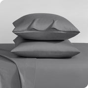 Two sateen pillowcases stacked on a bed
