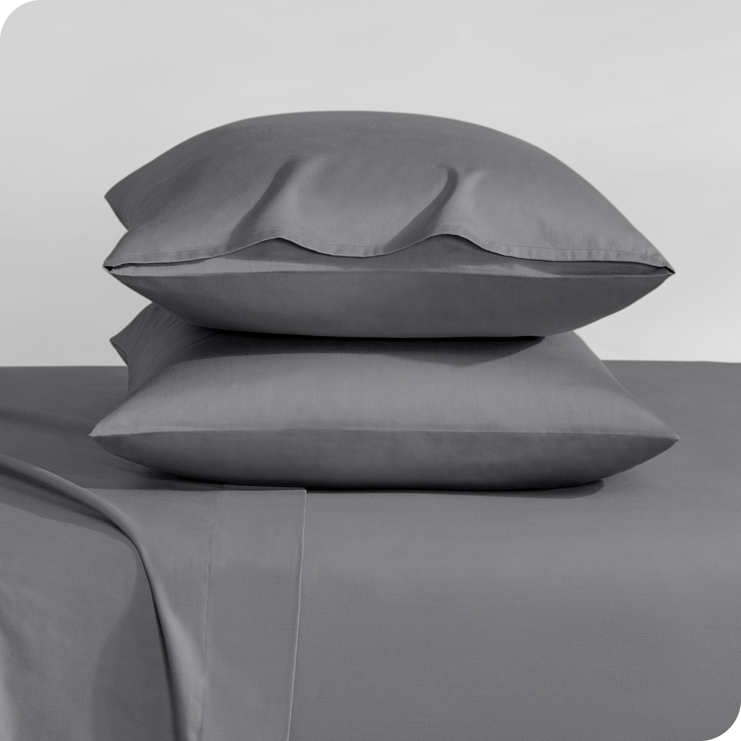Two sateen pillowcases stacked on a bed