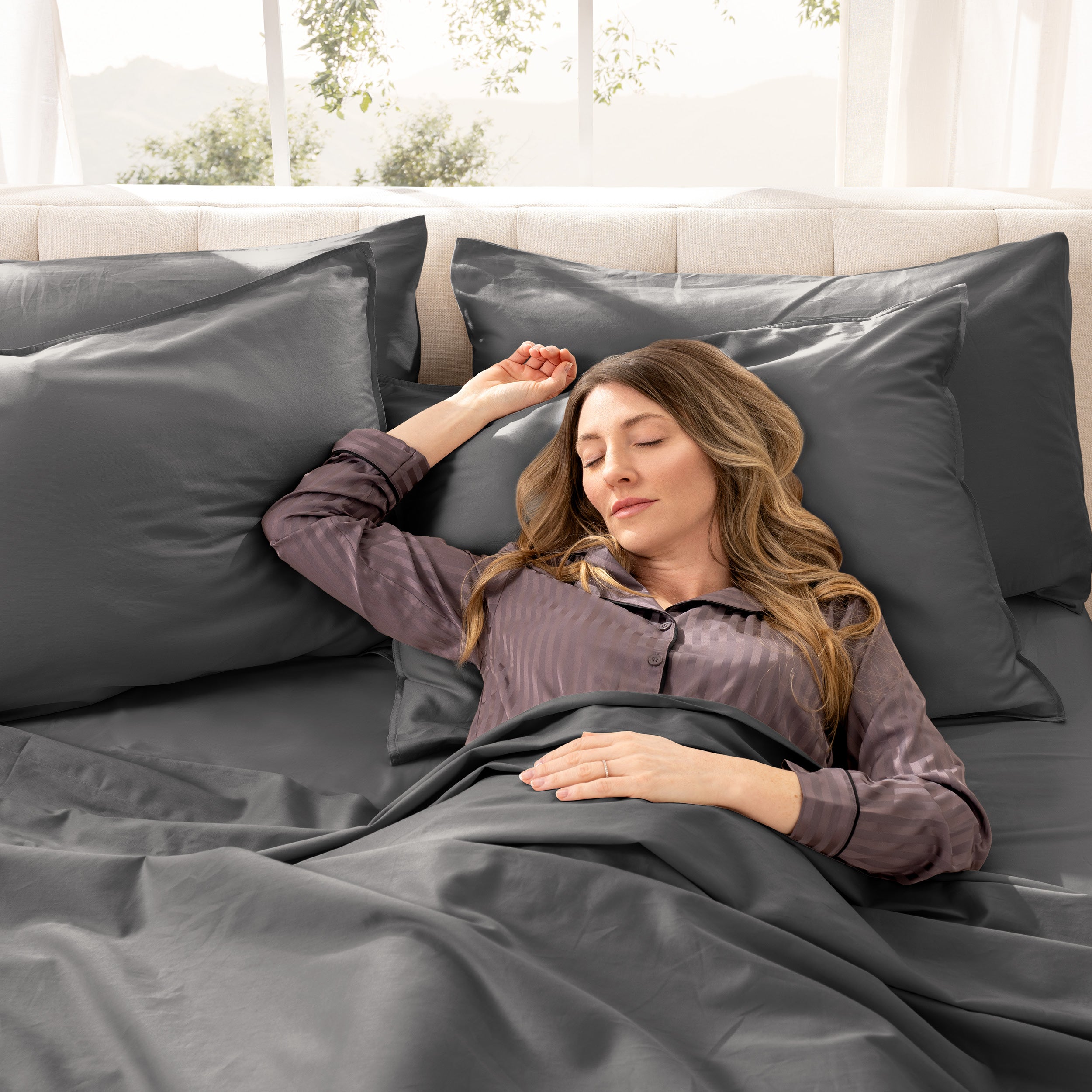 A woman sleeping on a bed made with organic cotton sateen sheets and pillowcases
