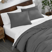 A bed made with an organic jersey duvet cover, pillow sham covered pillows and extra pillows