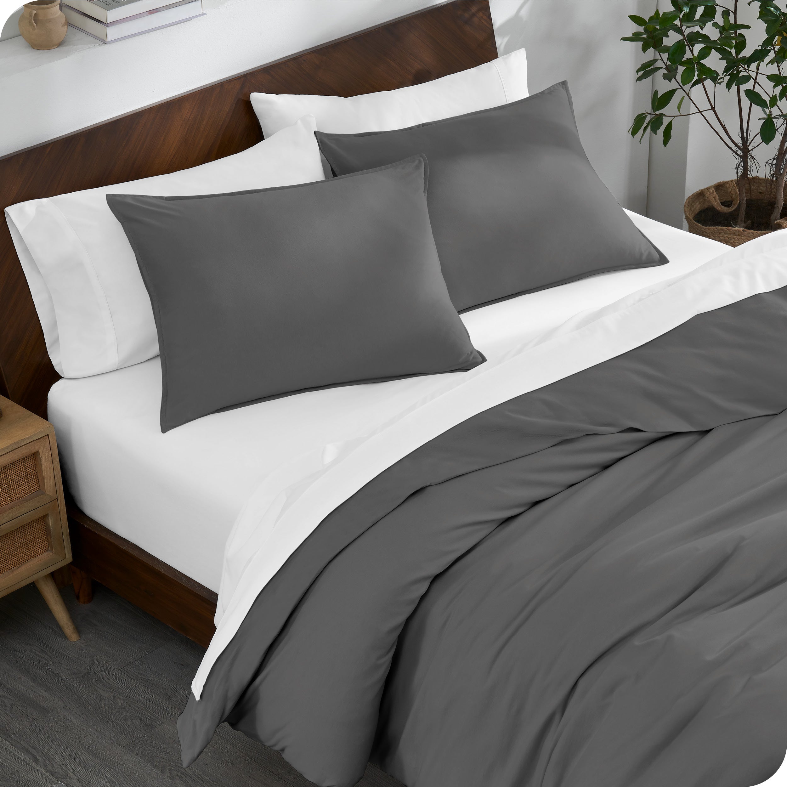 A bed made with an organic jersey duvet cover, pillow sham covered pillows and extra pillows