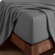 Close up of the corner of a mattress with a fitted sheet and flat sheet on it
