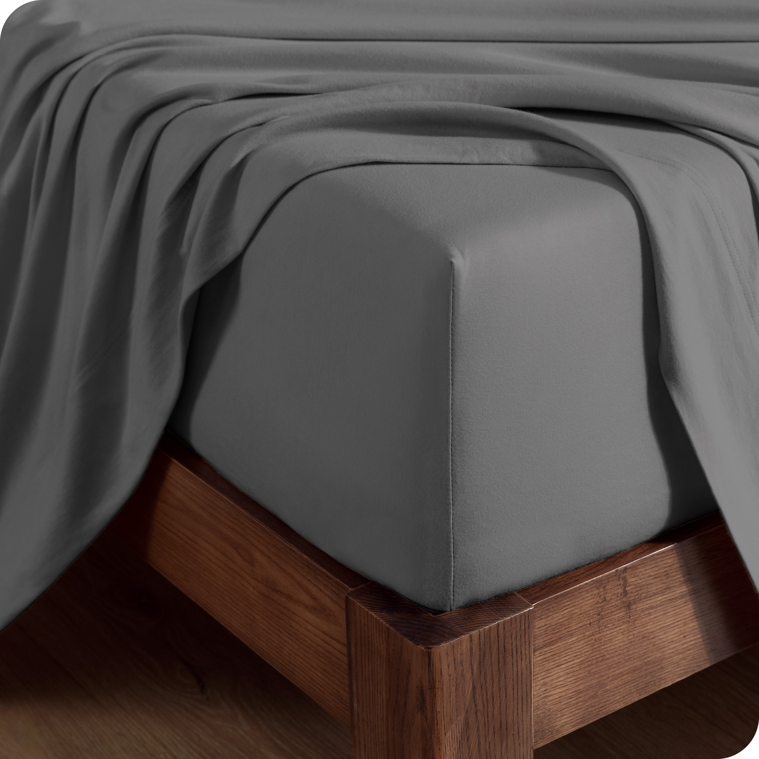 Close up of the corner of a mattress with a fitted sheet and flat sheet on it