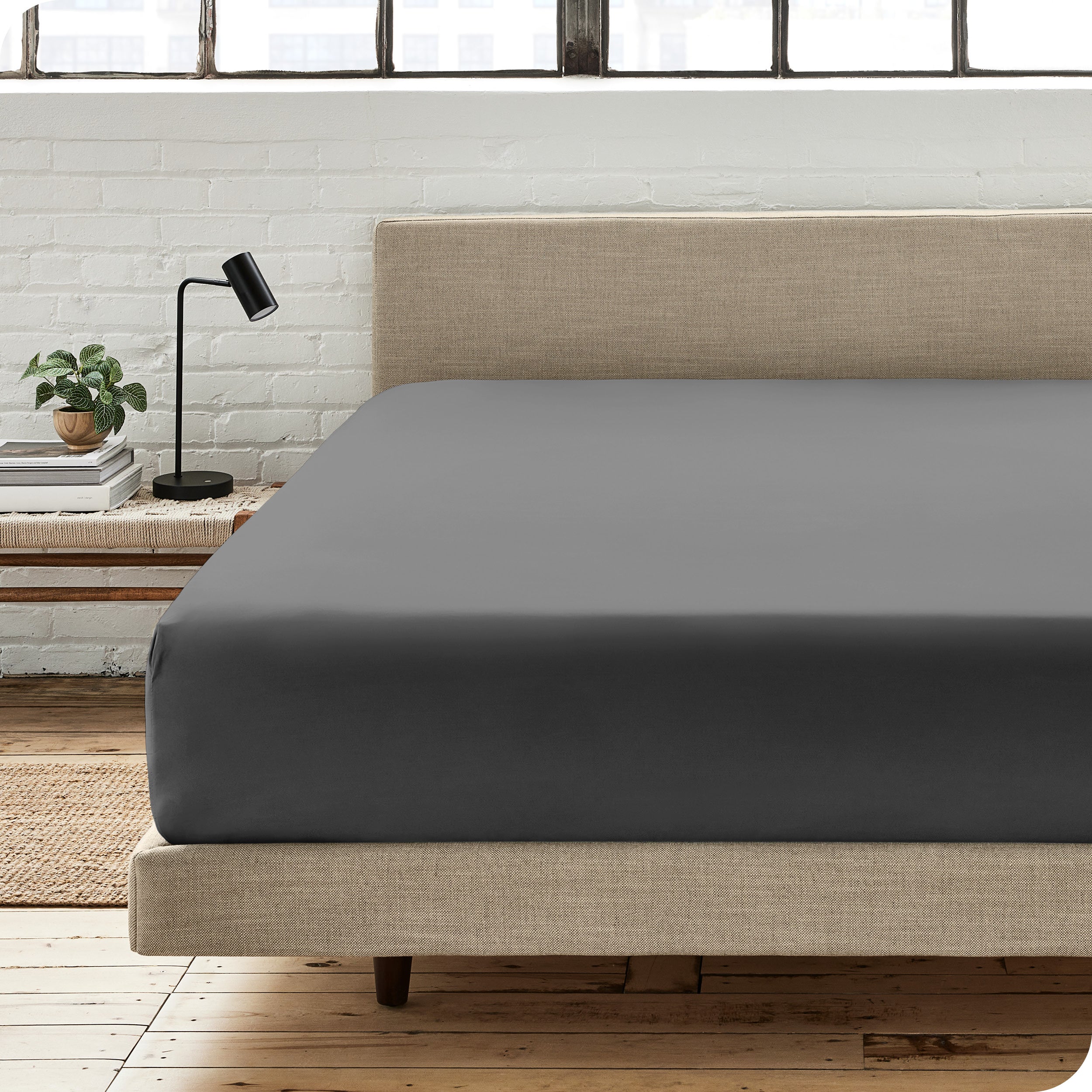 A percale fitted sheet on a bed with table next to it