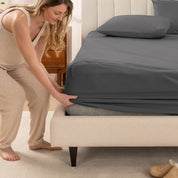 A women is putting on the percale fitted sheet on the bed