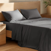 Organic cotton percale sheet set on a bed, with a flat sheet, fitted sheet, and two pillowcases displayed.