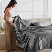 A woman making a bed with satin sheets