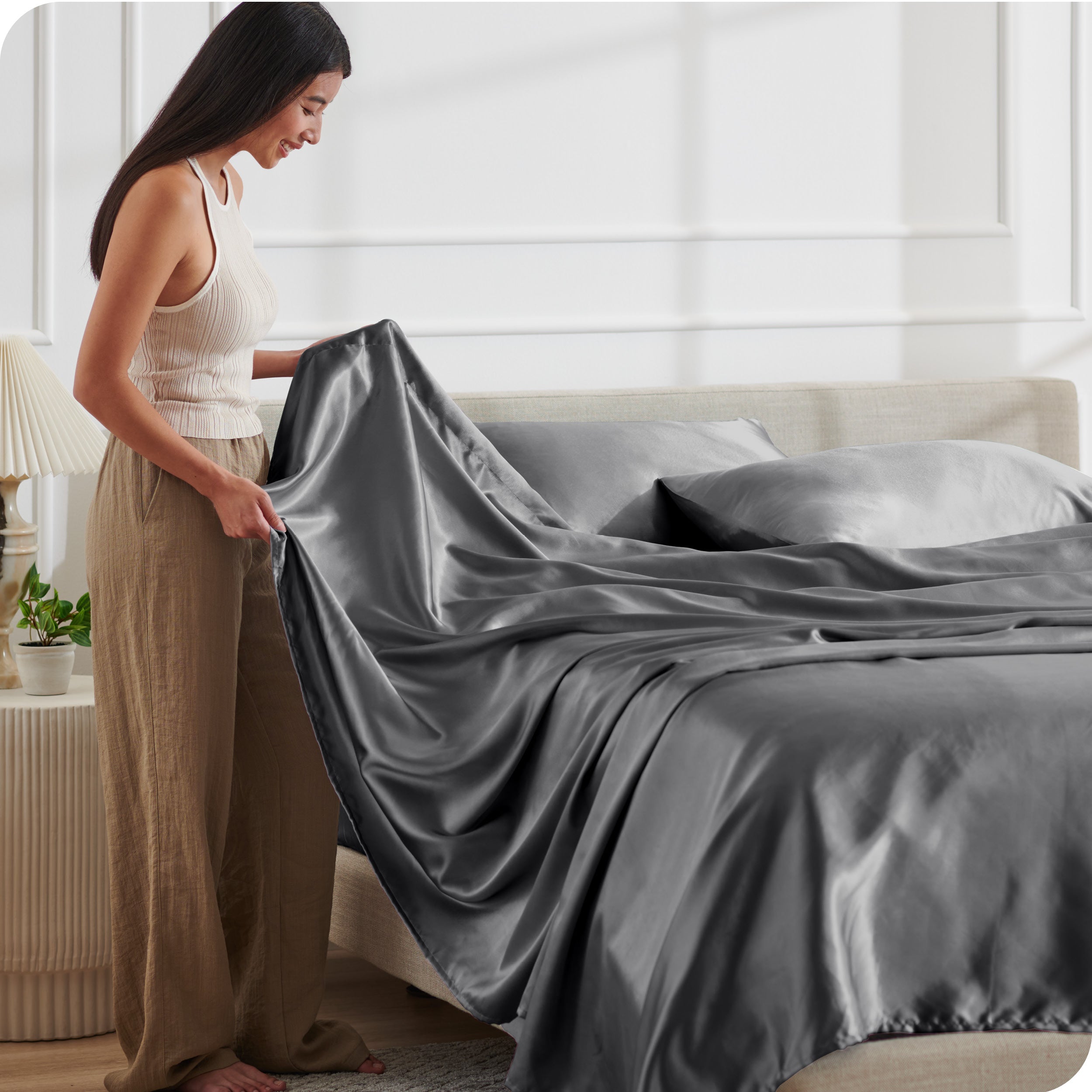 A woman making a bed with satin sheets