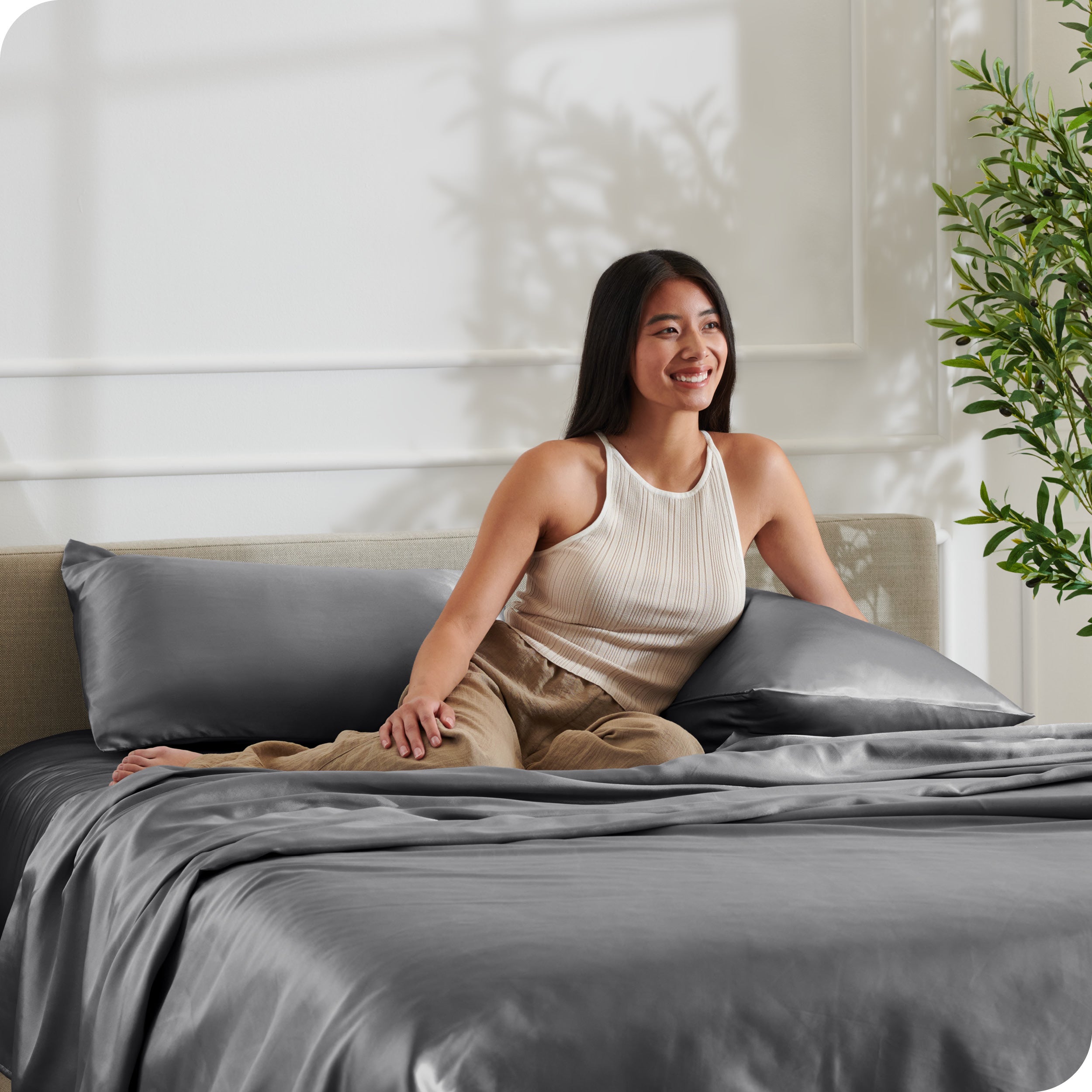 A woman sitting on a bed made with satin sheets