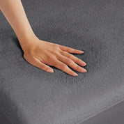 A hand is feeling the texture of the mattress protector.