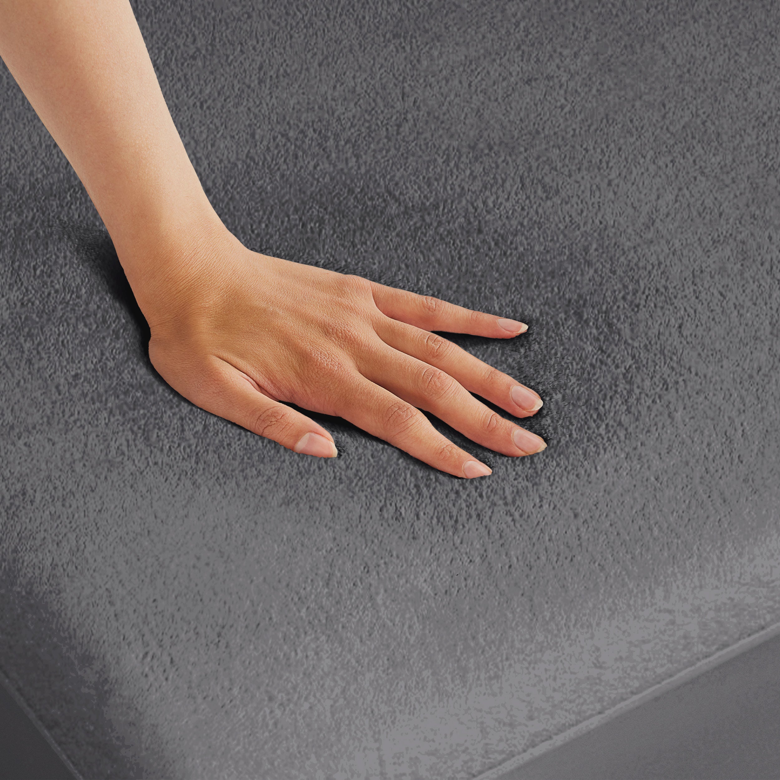 A hand is feeling the texture of the mattress protector.
