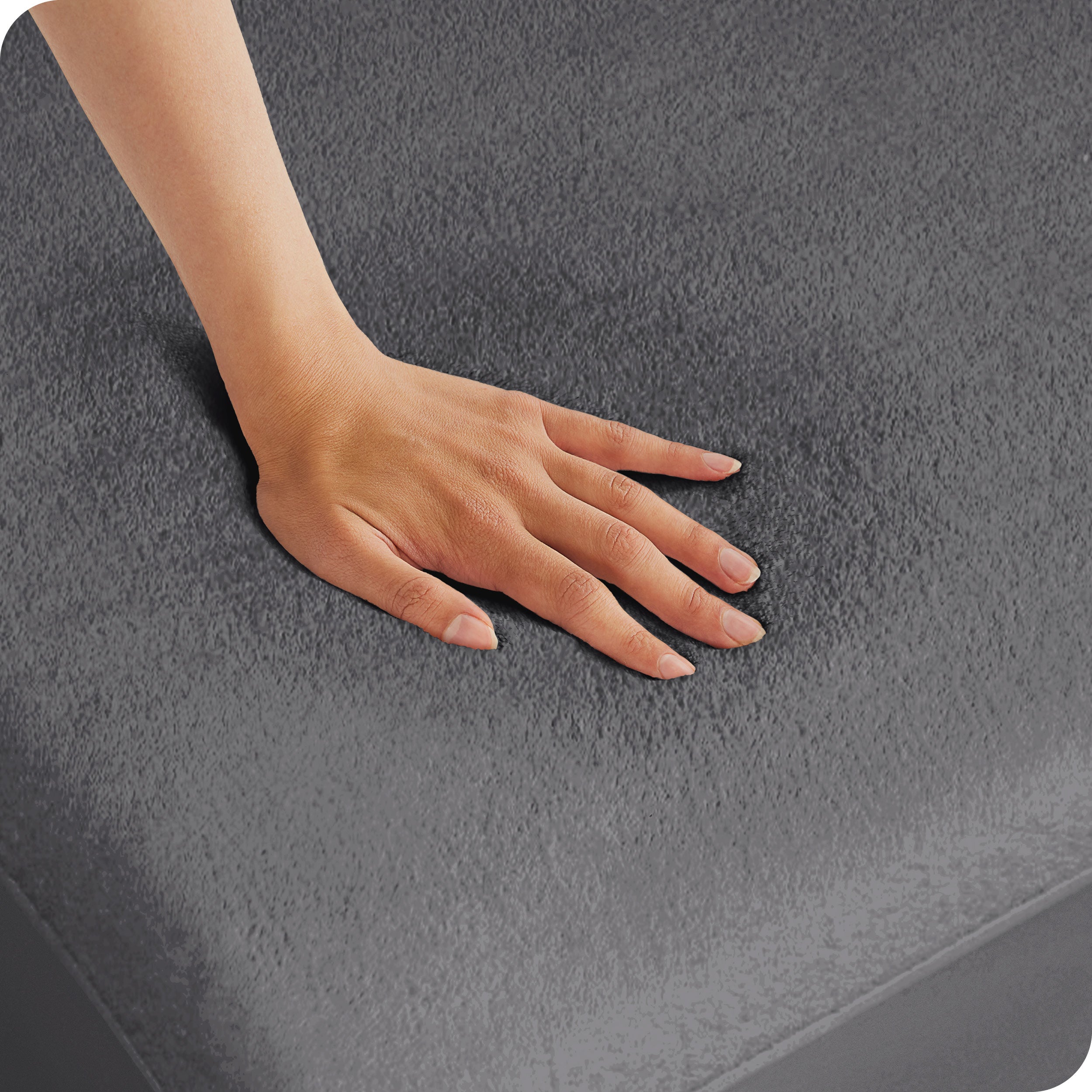 A woman is pressing her hand down on a mattress with a protector on it