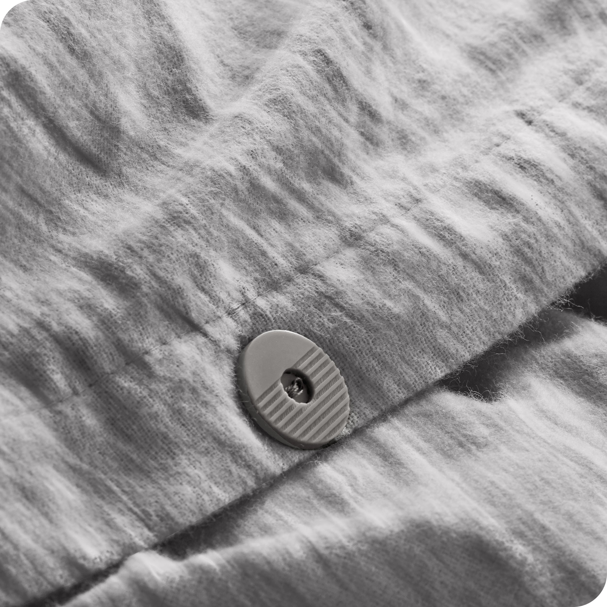A close up of the flannel duvet cover showing the button, lining, texture, and pattern.