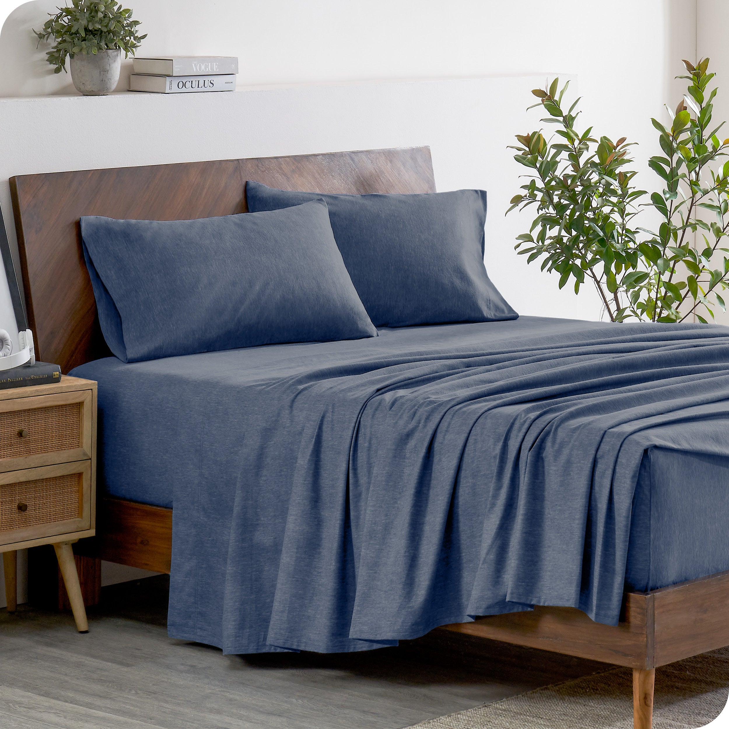 A wooden bed frame with heathered flannel sheets and pillowcases on the mattress