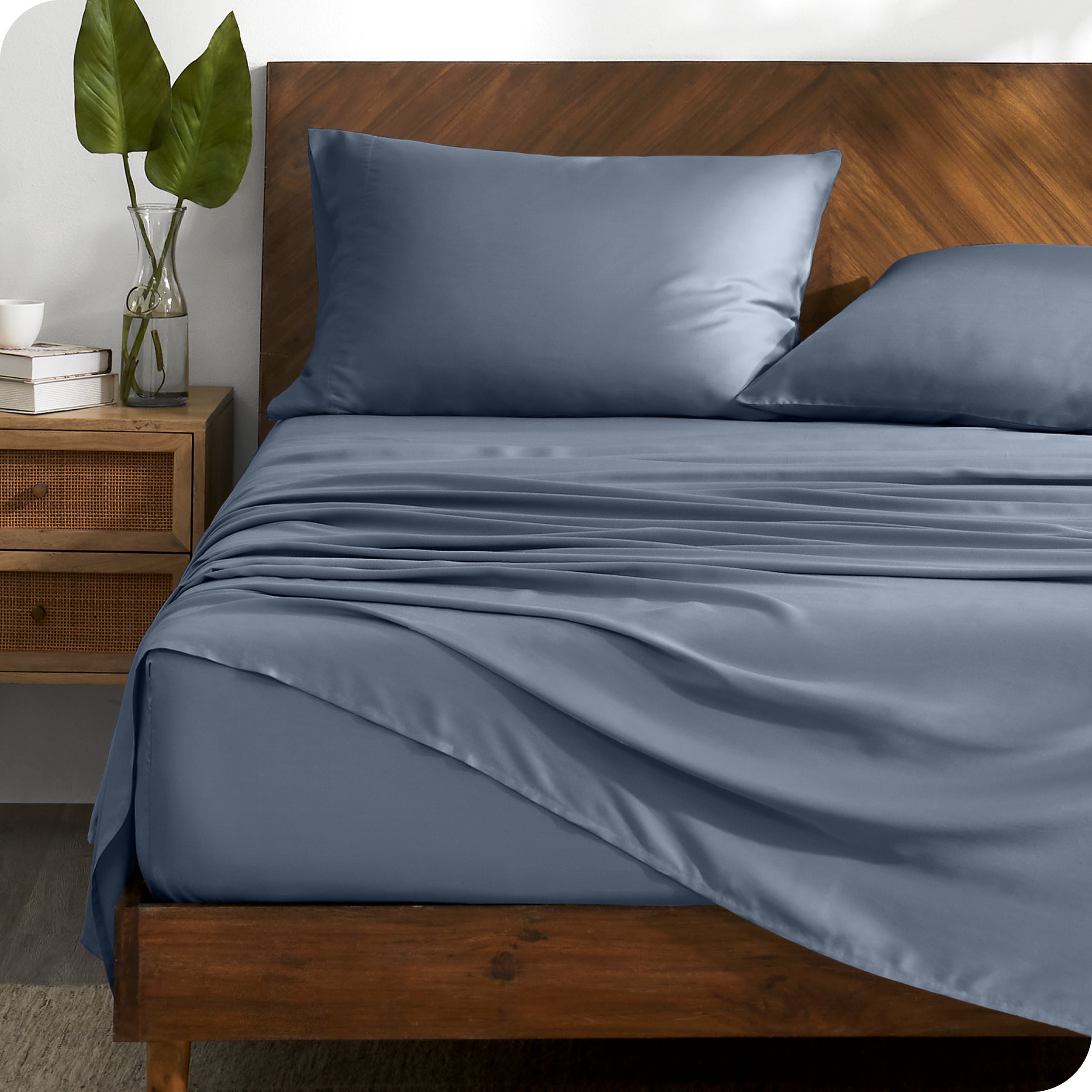 TENCEL™ sheet set on a bed with the flat sheet loosely draped over the top. The mattress is on a wooden bed frame.