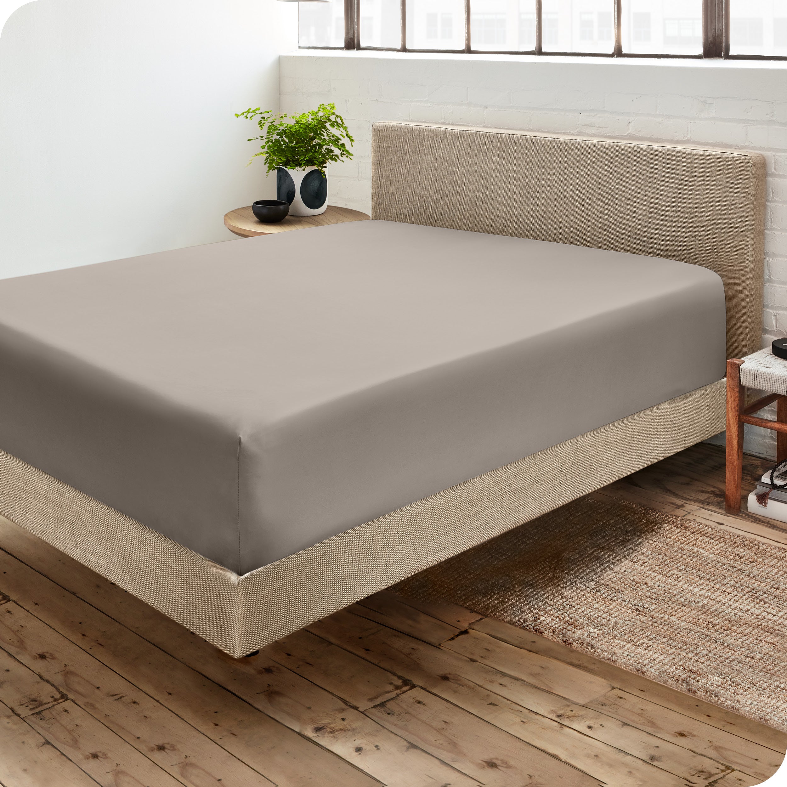 Corner view of a modern bed with a microfiber fitted sheet on the mattress. 