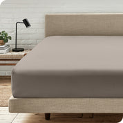 A bed with a microfiber fitted sheet on the mattress. 