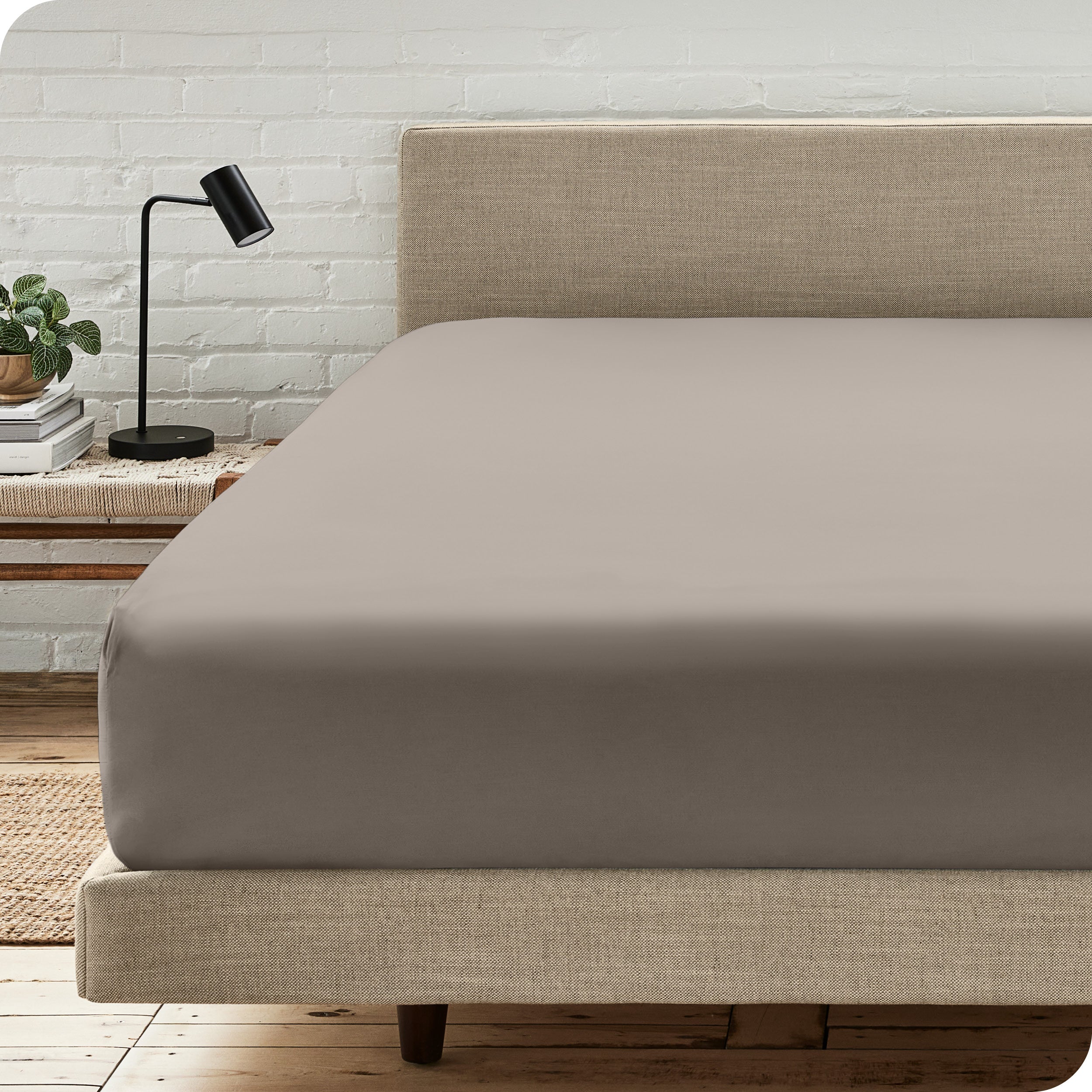 A bed with a microfiber fitted sheet on the mattress. 